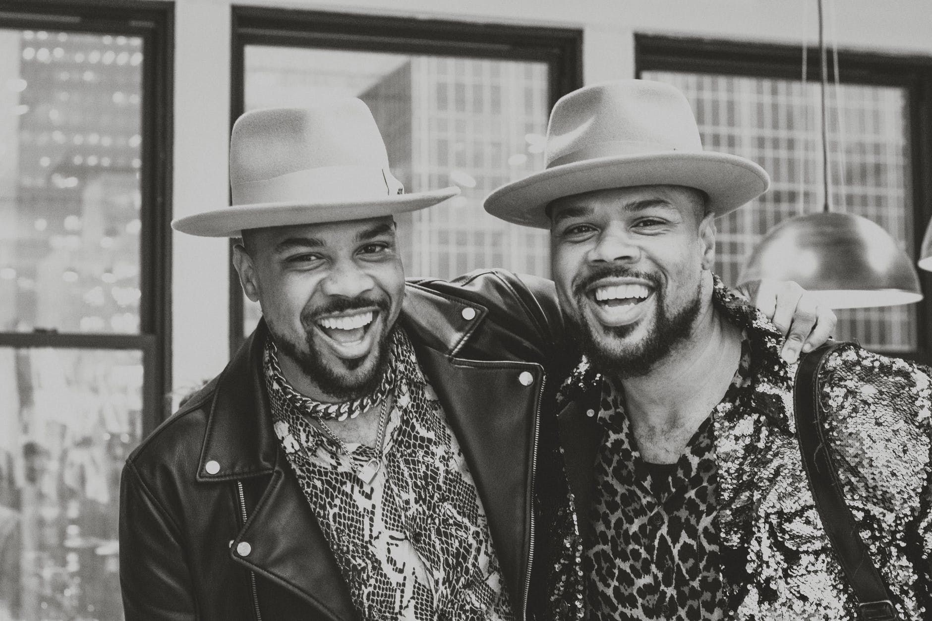 grayscale photo of male twins in same fedora hats standing together
